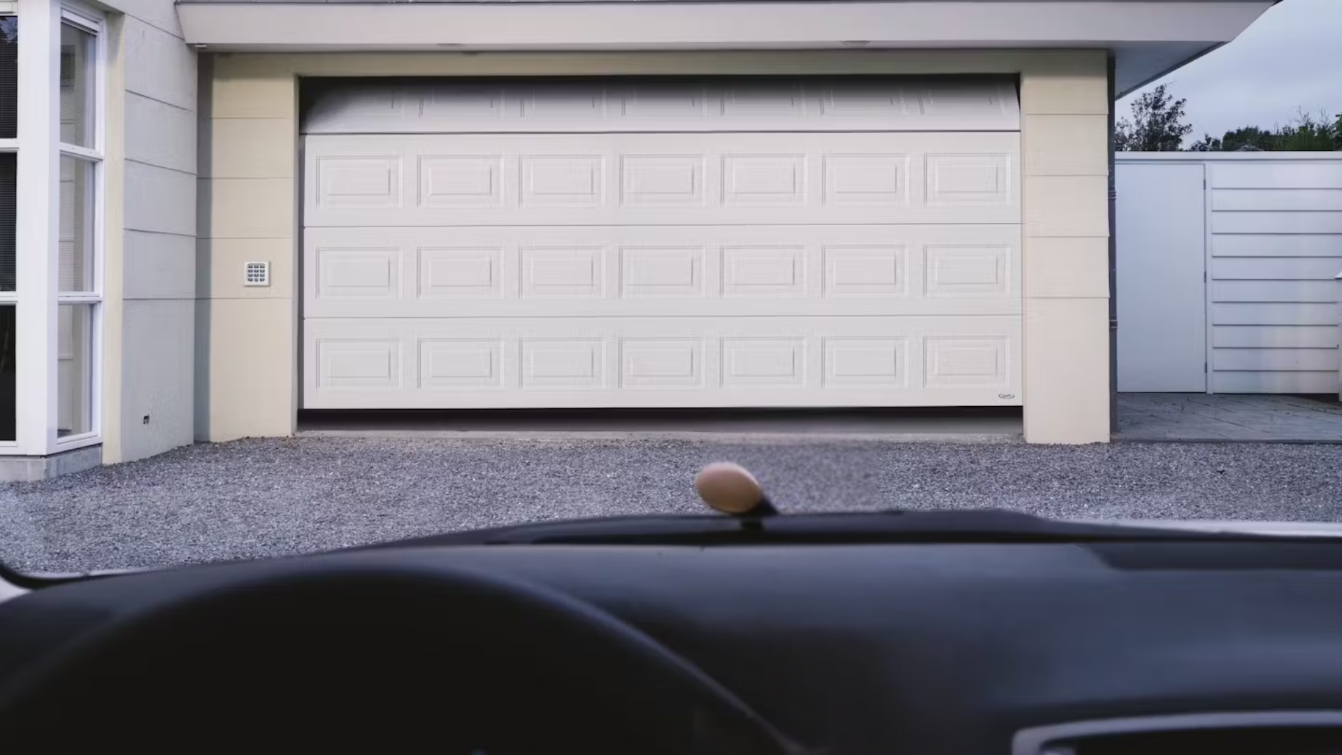 A car parked outside the a half-opened garage door